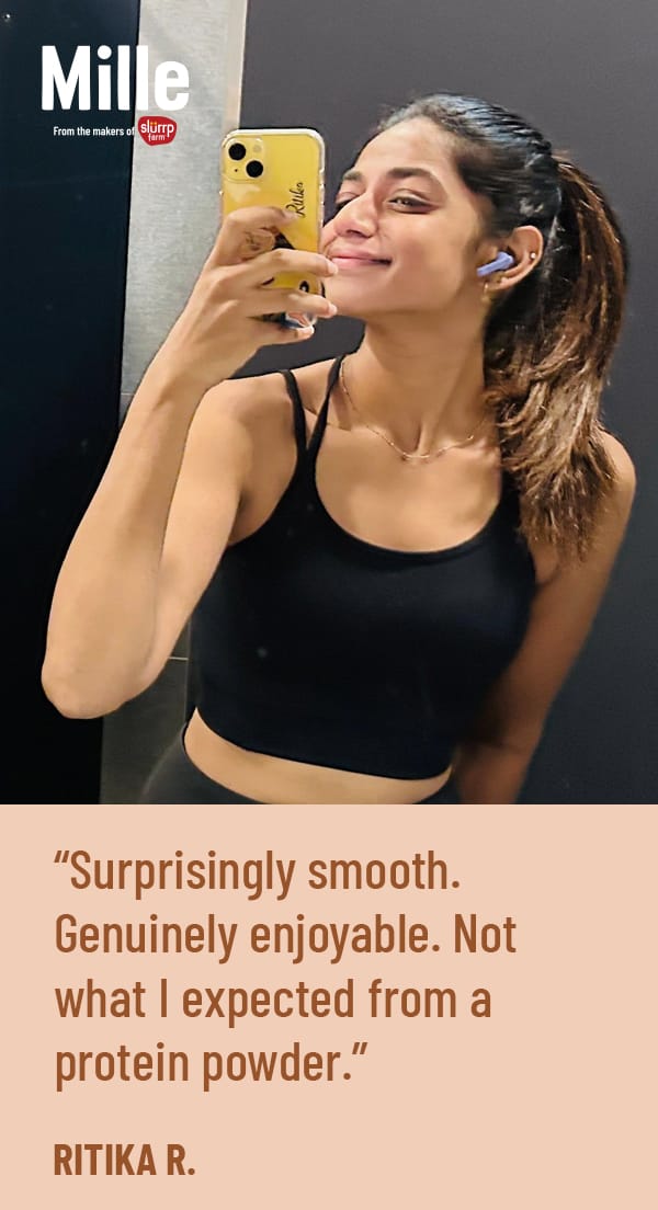 Woman taking a selfie with a phone, wearing a black sports bra and blue earbuds, with a Mille protein powder advertisement.