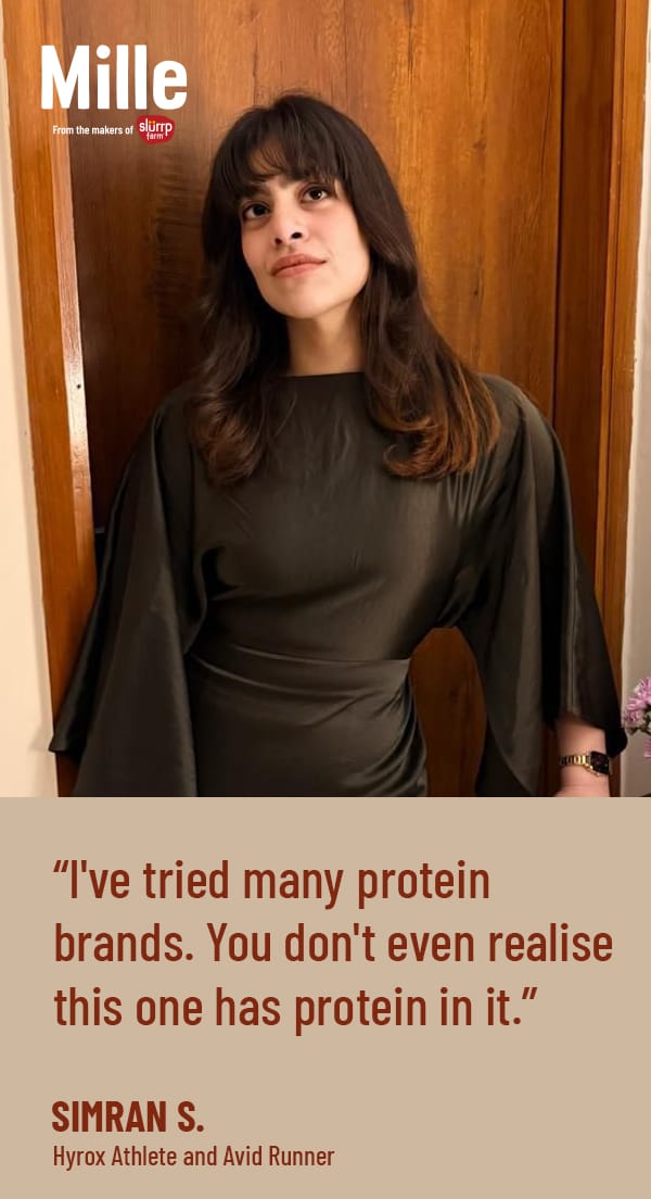 Woman in a dark green dress standing in front of a wooden door with a quote about protein brands.