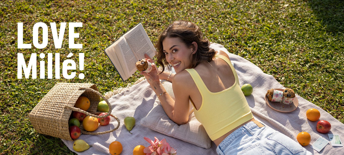 Woman reading a book on a picnic blanket with fruits and a bag, featuring 'LOVE Millé!' text.