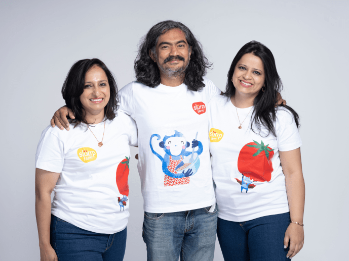 Three people wearing white t-shirts with colorful designs on a plain background